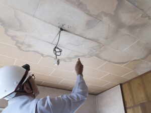 雨漏りした天井を調査するビジネスマン　住宅